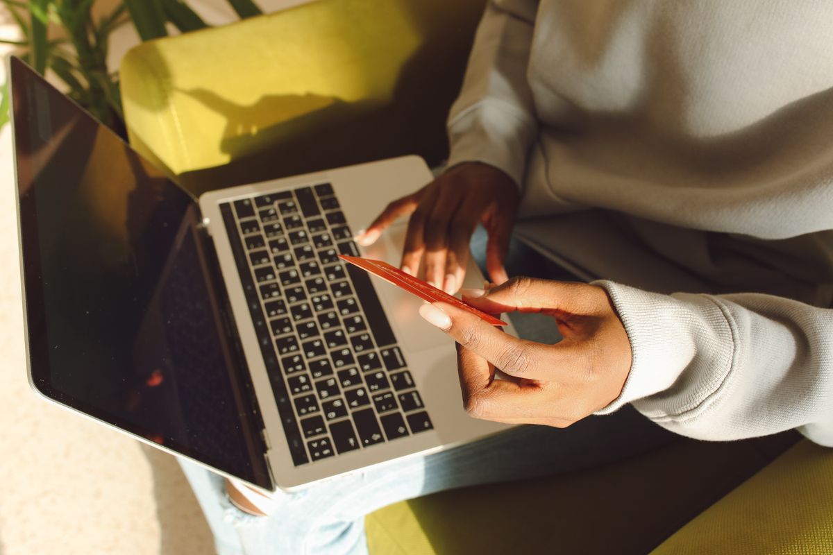 Pessoa segurando cartão enquanto utiliza um notebook para uma compra online